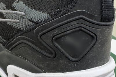 Before: white mould spotting across the heel counter of a black knit trainer